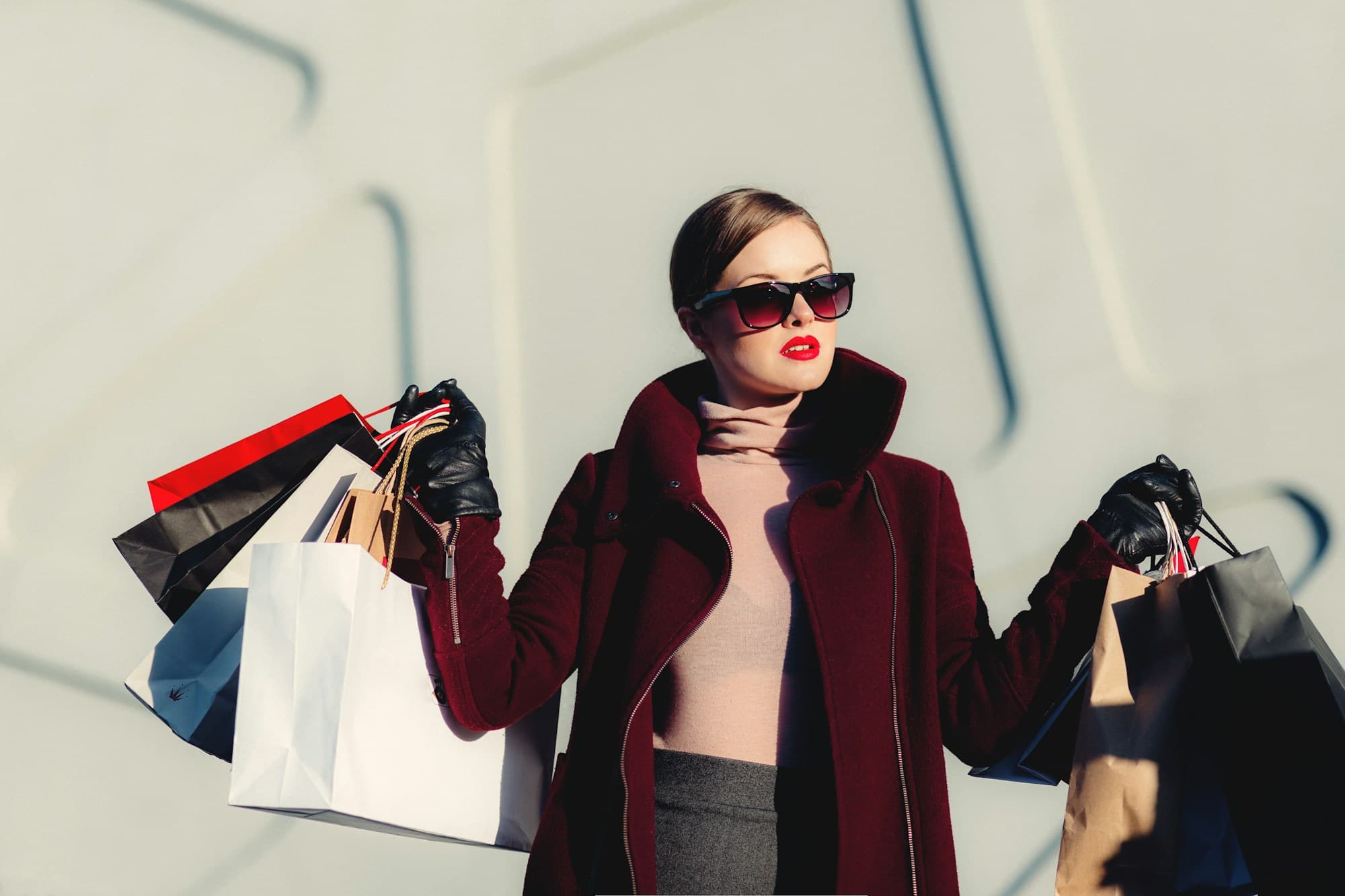Fashion in the city: a burgundy coat, statement sunglasses and shopping bags